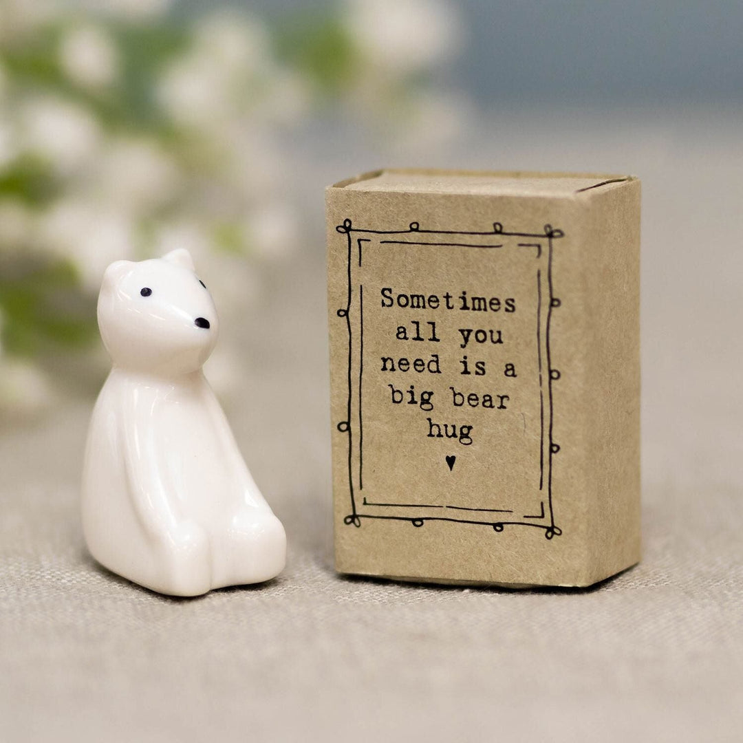 Small white bear figurine next to a brown box with a quote on a blurred background